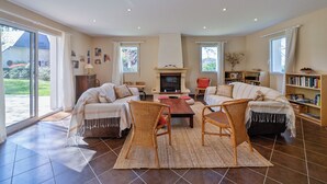 Ein geräumiges Wohnzimmer mit Kamin, zwei Sofas, einem Couchtisch und einem Bücherregal.