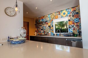 A kitchen with a colorful tile backsplash, a modern light fixture, and a built-in dishwasher. - Ocean bliss, infinity pool, beach front, inhouse restaurant, with parking. (Puerto Vallarta)
