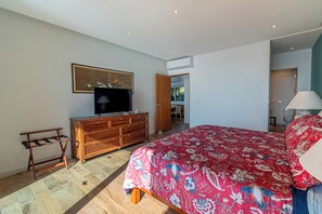 A bedroom with a bed, a TV, a dresser, and a door leading to another room. - Ocean bliss, infinity pool, beach front, inhouse restaurant, with parking. (Puerto Vallarta)