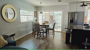 Una cocina moderna con comedor, ventanas amplias y un refrigerador.