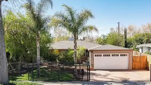 Una propiedad residencial con patio cercado, garaje y una casa de techo inclinado.