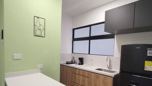 A kitchen with a white countertop, wooden cabinets, a black refrigerator, and a window with blinds. - Cozy loft in the best area of Laureles ***** (Medellin)