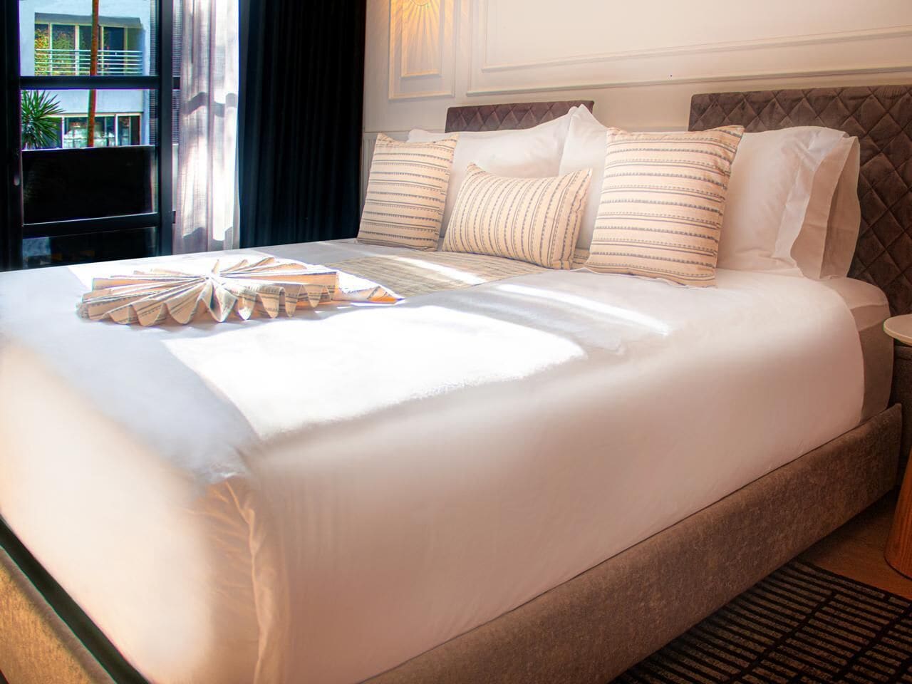 A large bed with a headboard, multiple pillows, and a bedside table.