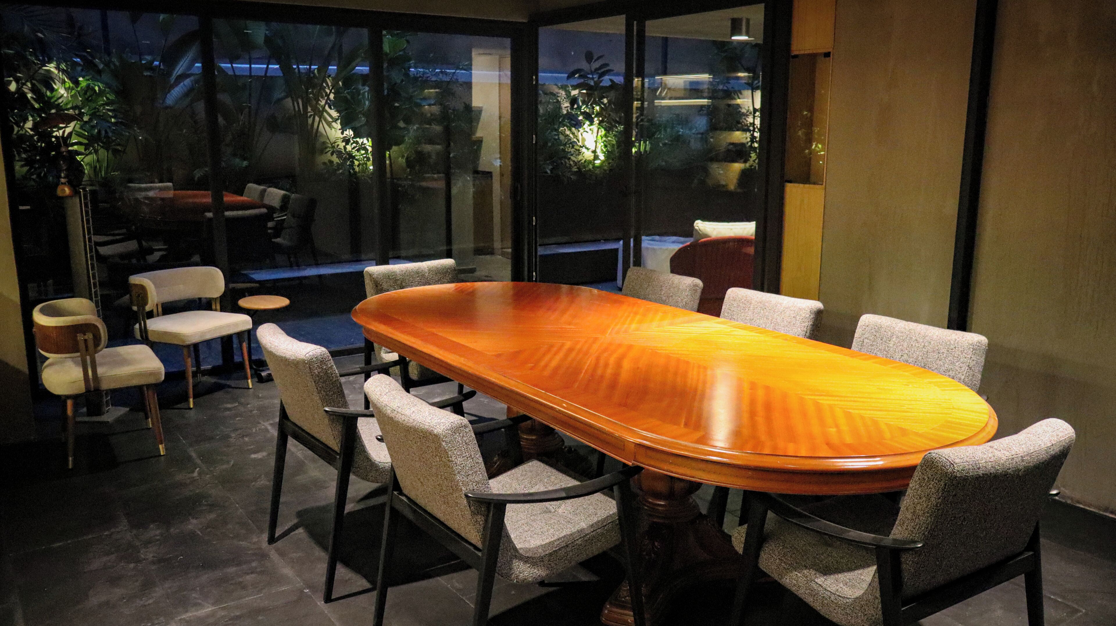 Un salón de conferencias con una larga mesa de madera, seis sillas y un separador de vidrio.