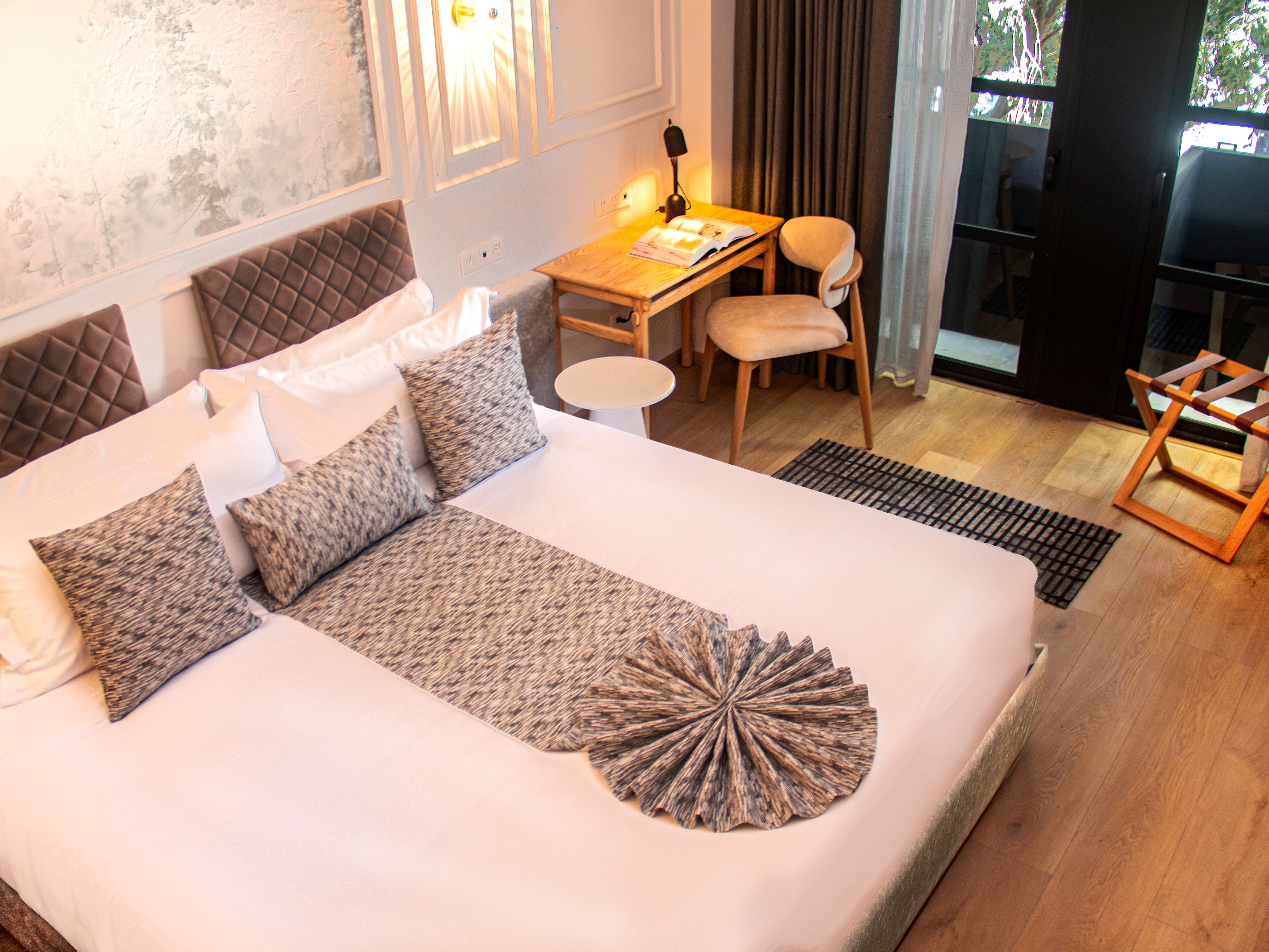 Een hotelkamer met een groot bed, een bureau, een stoel en uitzicht op de omgeving.