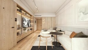 Una sala de estar moderna con un sofá, una mesa de centro y un televisor. Hay un mueble de madera con estantes y un radiador en la pared.
