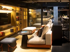 Un intérieur moderne avec un canapé, un pouf et un coin bar.