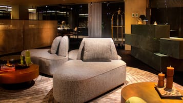 A modern hotel lobby with a sectional sofa, a round coffee table, and a reception desk.