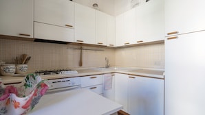 Une cuisine avec des meubles blancs, une cuisinière à gaz et un évier.