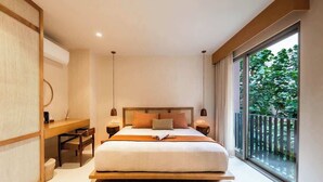 A modern bedroom with a large bed, bedside tables, a desk, and a view of greenery through a large window. - Executive Unit in Aldea Zama and Parking (Tulum)