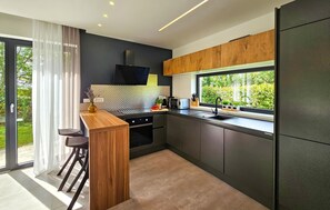 Eine moderne Küche mit großem Fenster, dunklen Schränken und einer Holztresore.