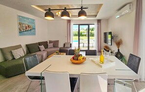 Ein modernes Wohnzimmer mit einem großen Esstisch, einer Couch und einem an der Wand montierten Fernseher.