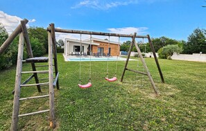A wooden swing set in a grassy yard with a pool and a modern house in the background. - Gorgeous home in Zminj (Zminj)