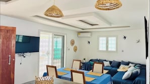 Une pièce comprenant une table à manger, un canapé bleu et deux lampes suspendues en osier.