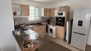 Une cuisine moderne dotée d’un îlot central, de meubles en bois, d’un four encastré et d’un réfrigérateur blanc.