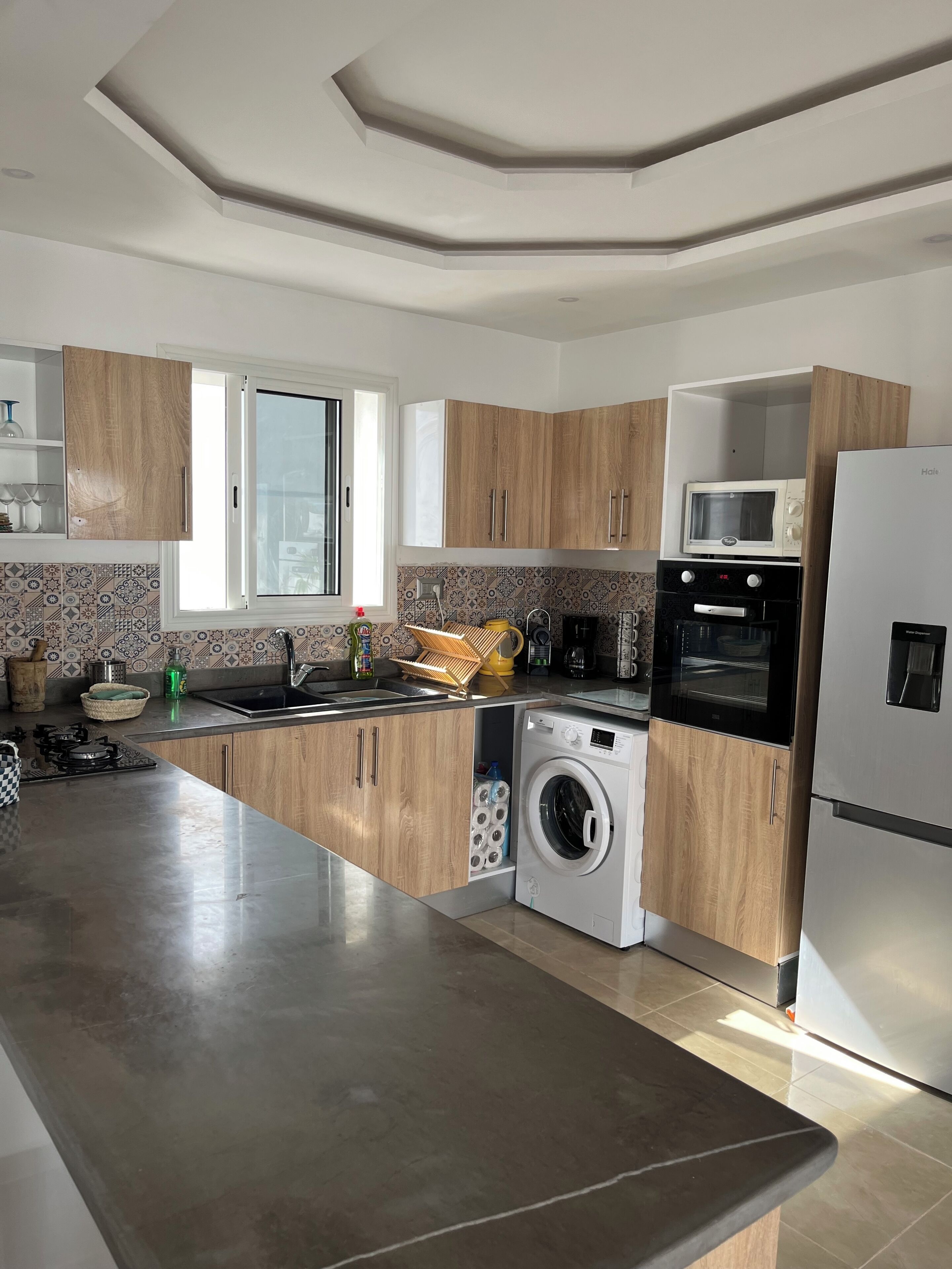 Een moderne keuken met houten kastjes, een ingebouwde magnetron, oven en wasmachine.