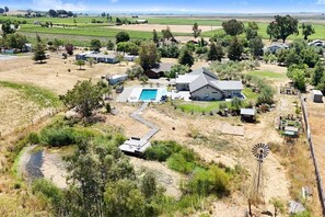 Ein großes Haus mit Schwimmbecken, umgeben von Feldern und einer Windmühle.
