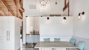 Una cocina moderna con armarios blancos, una mesa de comedor de madera y un banco empotrado con cojines.