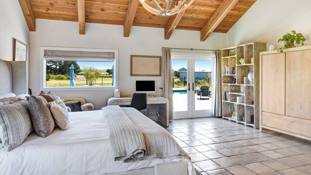 Un dormitorio con cama, escritorio, computadora y vistas al exterior.