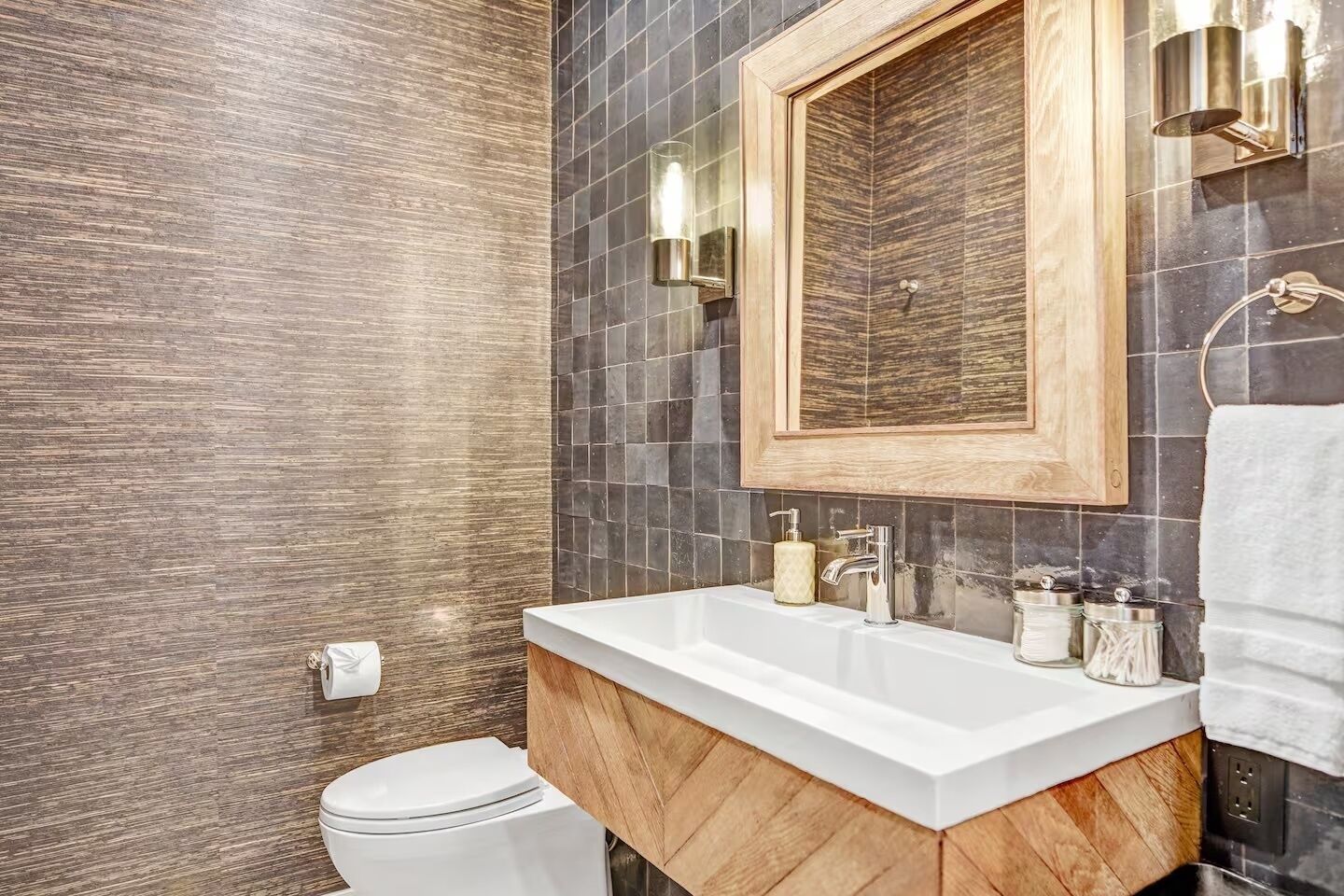 Une salle de bain avec un meuble-lavabo en bois, un lavabo blanc, un miroir et des toilettes.