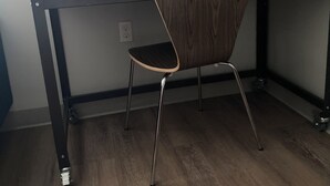 Un bureau d’angle avec un bureau, une chaise et une étagère au-dessus.