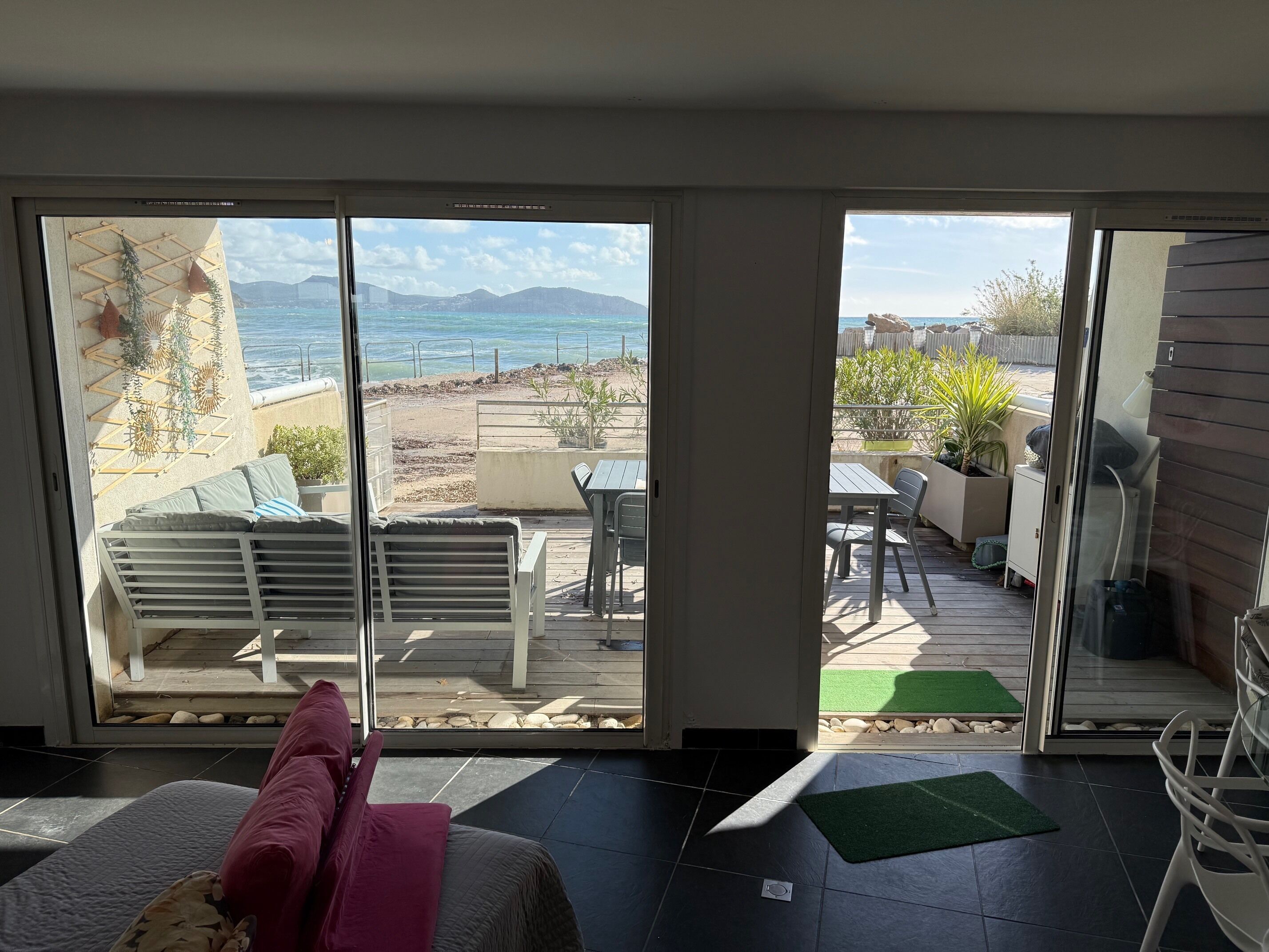 Ein Zimmer mit Meerblick, eine Terrasse mit Gartenmöbeln und eine Glastür.