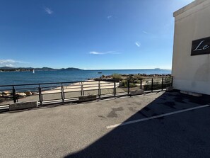 A coastal view with a clear sky, a paved walkway, and a sign reading 'Le'. - Waterfront apartment, the sea 10 metres away! (La Ciotat)