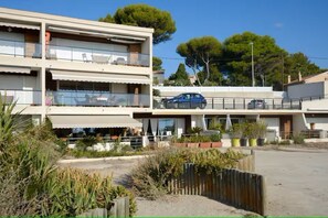 A multi-story building with balconies, a parking area, and surrounding vegetation. - Waterfront apartment, the sea 10 metres away! (La Ciotat)