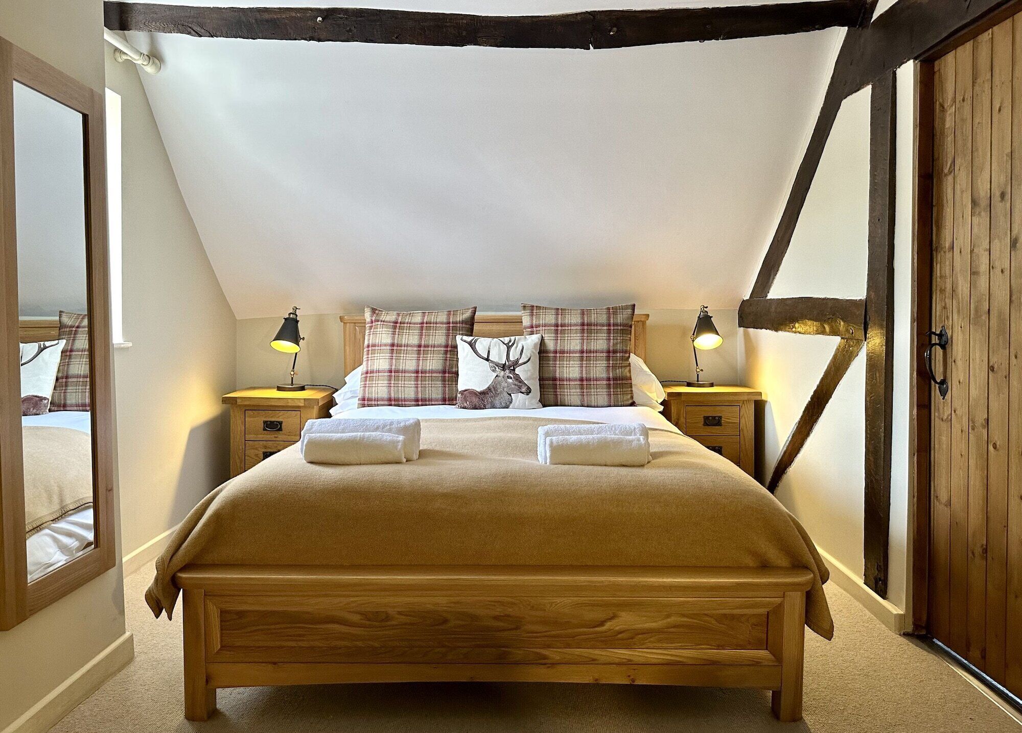 A bedroom with a wooden bed, two bedside tables with lamps, a window, and a door.