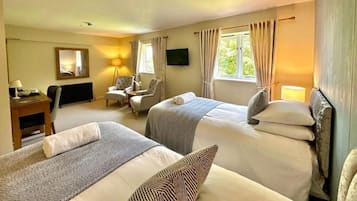 A hotel room with two beds, a desk, a chair, a TV, and a window with curtains.