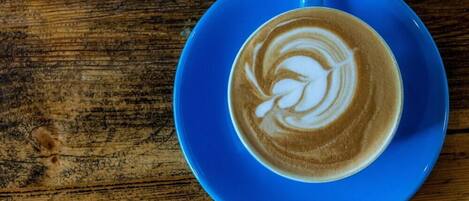 Una taza de café sobre un platito azul sobre una mesa de madera.