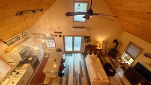 Una stanza con soffitto alto, un'area pranzo, una cucina e una zona relax.