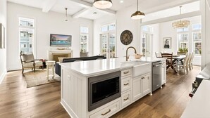 A spacious kitchen with a large island, white cabinetry, and a modern pendant light. - Tortuga House 105 SOU (Port Aransas)