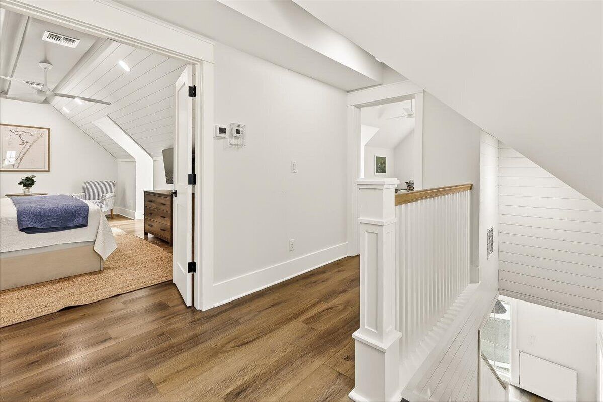 Un dormitorio con una cama, un aparador y una mesita de noche. Se ve una escalera que conduce a un nivel superior.