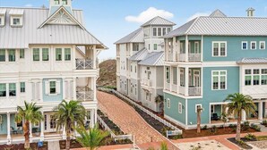 A coastal residential area with multi-story houses featuring balconies and a paved walkway. - Tortuga House 105 SOU (Port Aransas)