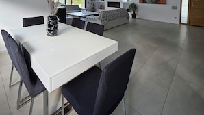 Amplia sala de estar moderna con una mesa de comedor, sillas, un sofá y un televisor.