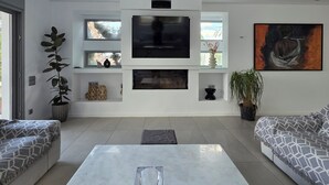 Una sala moderna con un televisor de pantalla plana grande, dos sofás, una mesa de centro y una planta en maceta.