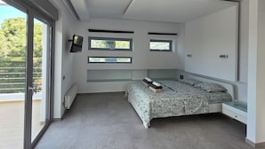 Un dormitorio moderno con una cama, estanterías empotradas, un televisor y un ventanal grande.