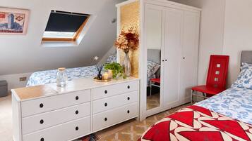 A bedroom with a bed, a dresser, a red chair, a wardrobe, a window, and a decorative wall piece.
