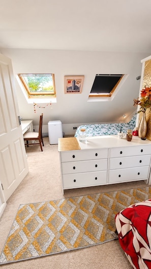 Een slaapkamer met een bed, een dressoir, een raam en een deur.