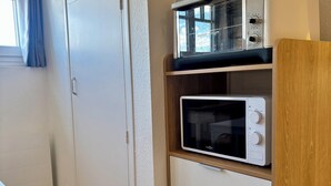 Uma cozinha compacta com micro-ondas, fogão e gavetas.