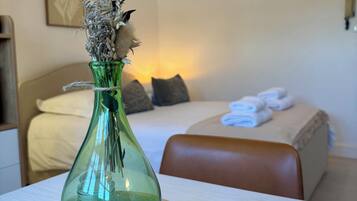 Eine grüne Vase mit getrockneten Blumen auf einem Holztisch in einem Hotelzimmer.