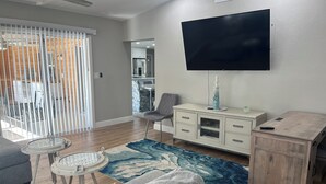 Un soggiorno con una televisione a schermo piatto, un mobile in legno, un tappeto decorato e un divano.