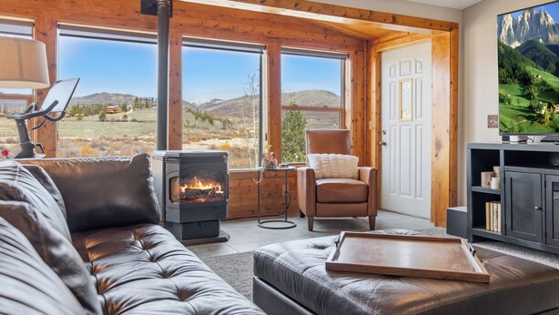 A cozy living room with a fireplace, leather sofa, and a television. - Aspen Grove Cabin - Sauna, 3 Decks, Mountain Views, ATV Access (Grand Lake)