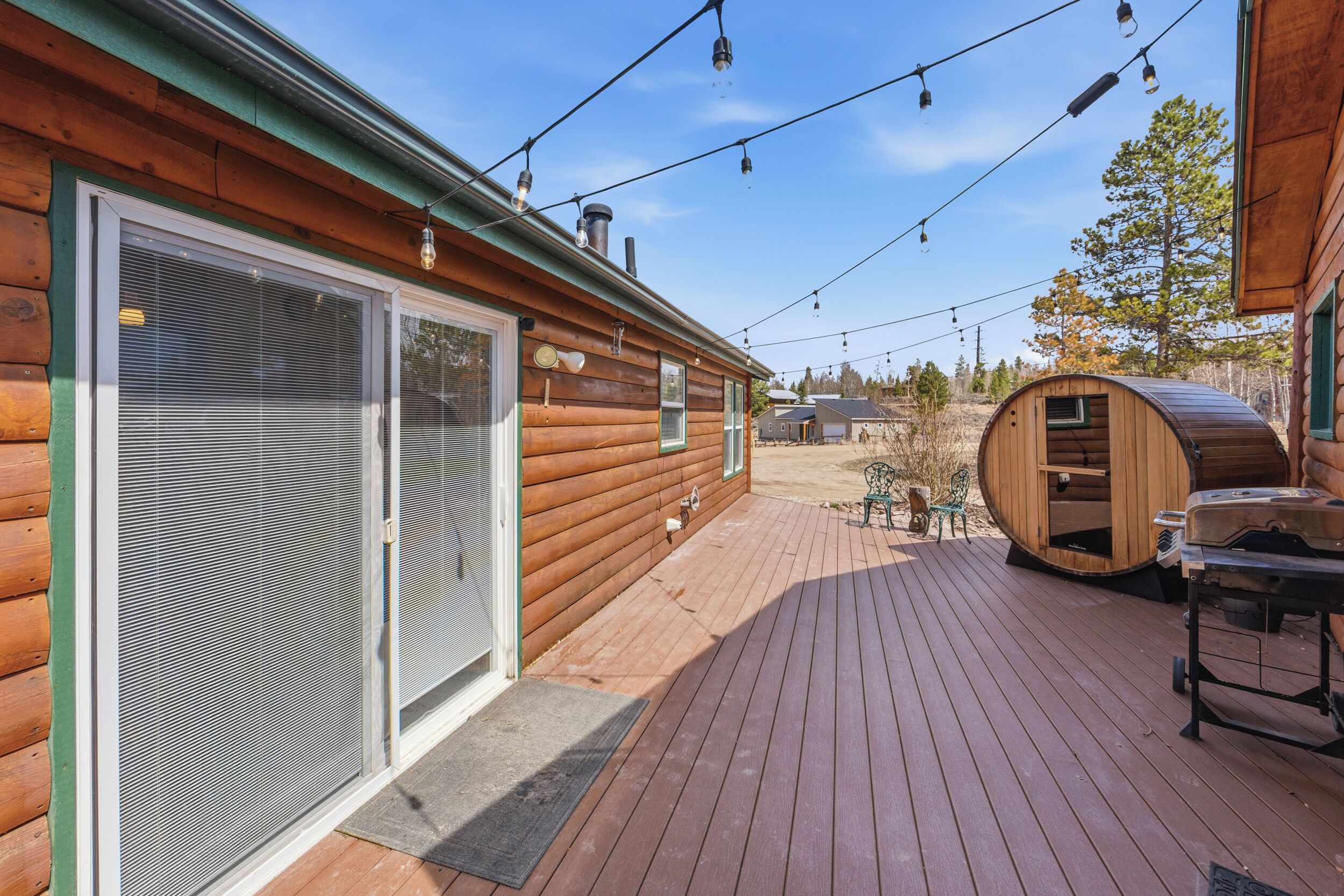 Une cabane en bois dotée d’une terrasse, d’un sauna et de guirlandes lumineuses.
