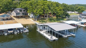 A lakeside property with a dock, a house, and a boat house. - 40’ Boat Slip-New Luxury Lakefront-3 King Beds-Sleeps 12-21MM (Osage Beach)