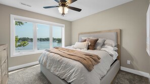 Quarto com uma janela grande, um ventilador de teto e vista para a água.