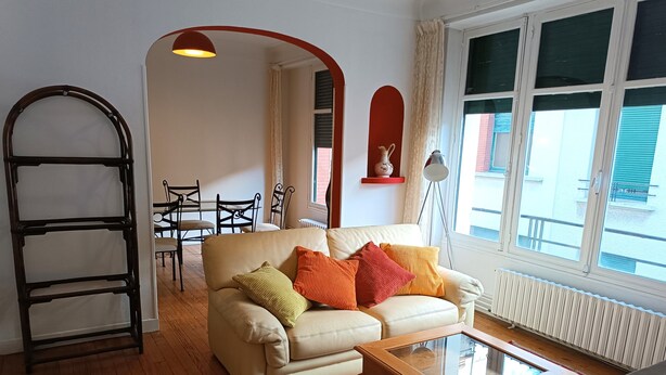 Een woonkamer met een bank, salontafel, kleed met een patroon en een ladder.