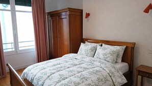 Een slaapkamer met een bed, een houten garderobe en een klein nachtkastje.
