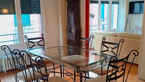 Een eethoek met een tafel met glazen blad en zwarte metalen stoelen.